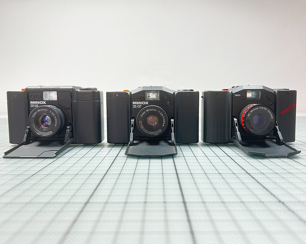 Polaroid-Sofortbildkameras in einer Reihe vor einer blauen Wand.